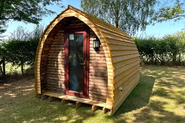 Wooden camping pod under the shade of trees