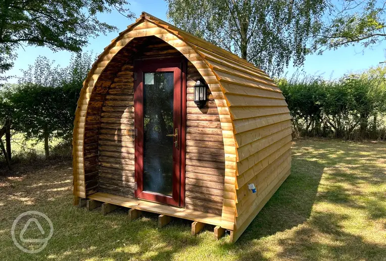 Wooden camping pod under the shade of trees