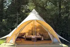 Bell tent on a wooden deck with a wood burner