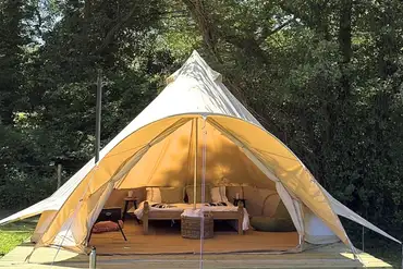 Bell tent on a wooden deck with a wood burner