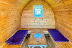 Camping pod (four person) interior with wrap around seating converting into beds Camping pod (four person) interior with wrap around seating converting into beds