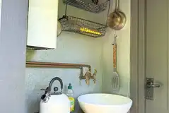 Shepherd's Hut kitchen area with gas stove, sink, crockery and cutlery