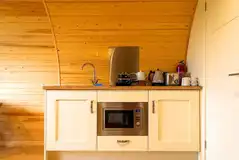 Glamping pod kitchen with a fridge, sink, toaster, microwave