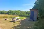 Grass pitch with fire pit, picnic bench and private toilet
