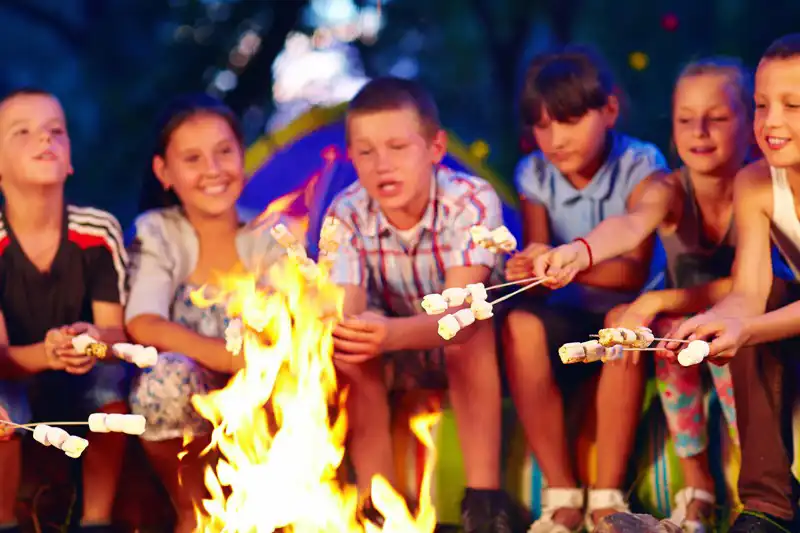 Roasting marshmallows around campfire kids camping activity