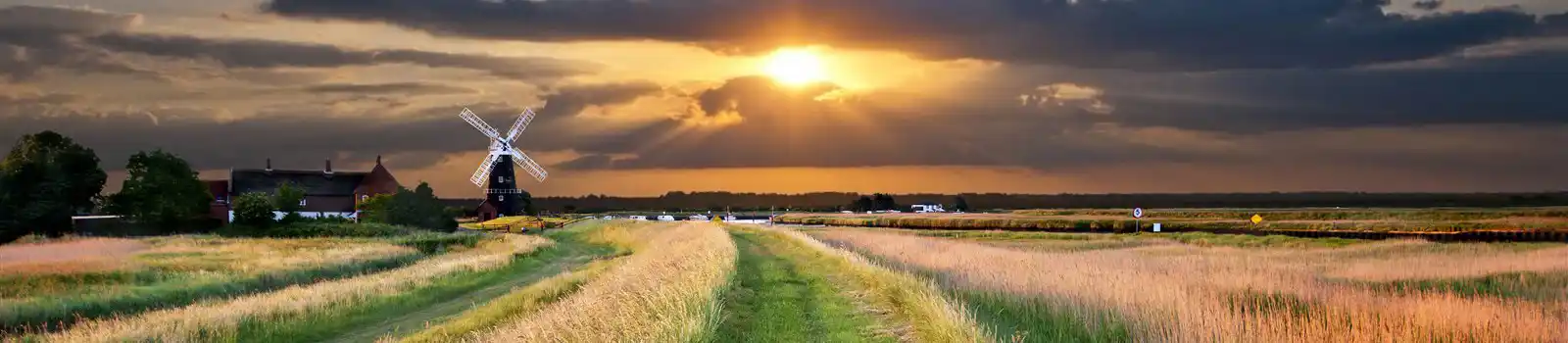 a traditional windmill pump on the Bure marshes of the norfolk broads in england, uk, with a beautiful, spectacular sunset in the background