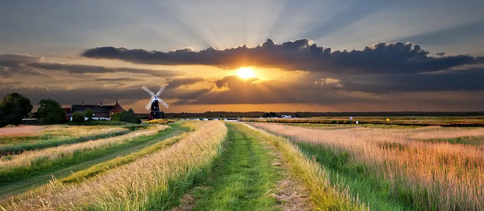 a traditional windmill pump on the Bure marshes of the norfolk broads in england, uk, with a beautiful, spectacular sunset in the background