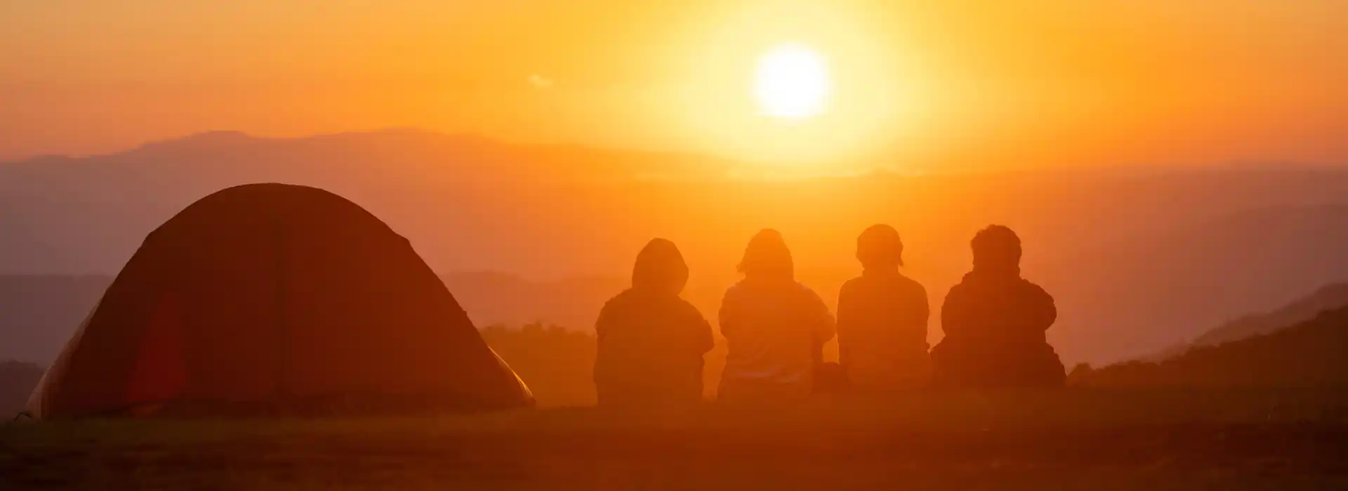 Group campers overlooking a sunset