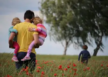 Young children being held by father in poppy field