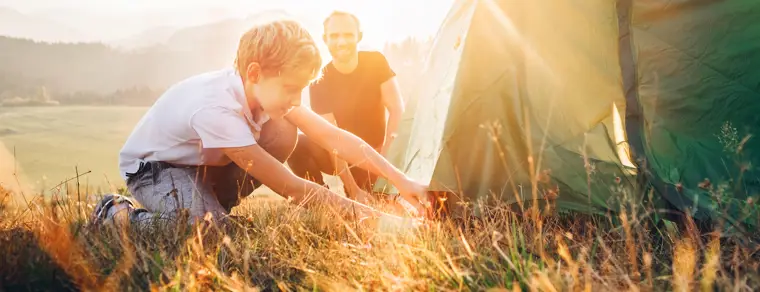 A father and son pitching their tent